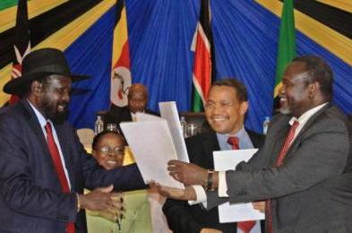 South Sudanese president Salva Kiir (L) exchanges signed documents with rebel leader Riek Machar in the northern Tanzanian town of Arusha on 21 January 2015 (AFP)