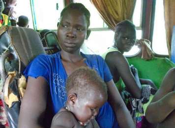 A South Sudanese refugee with her child on one of the buses that moved volunteers from the flood-prone Leitchuor and Nip Nip refugee camps in western Ethiopia (Photo courtesy of the UNHCR)