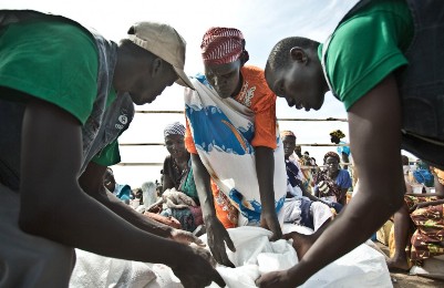 Oxfam aid workers in Mingkaman, South Sudan, oversee the distribution of food to displaced people in August 2014. (Photo Pablo Tosco/Oxfam)
