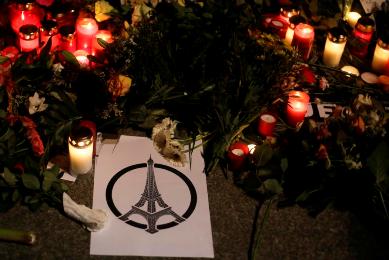A poster with the Eiffel Tower is displayed between candles for the victims killed in the Friday's attacks in Paris, France, in front of the French Embassy in Berlin, Saturday, Nov. 14, 2015. (Photo AP)