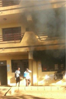 black smoke rising from a building of the University of Quran in Omdurman as two people spray water trying to control fire on 11 November 2015 (ST Photo)