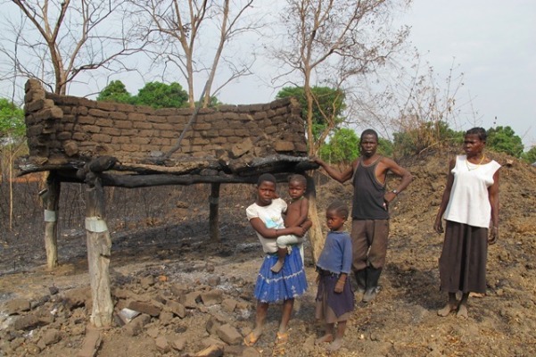 A family stands beside the burnt granary store in Western Equatoria's Tombura  County on 19 Feb 2016 (ST Photo)