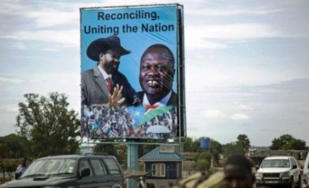 Pedestrians and traffic move past a billboard featuring portraits of President Salva Kiir (L) and SPLM-IO leader Riek Machar in Juba, on April 14, 2016. (Photo AFP/Albert G. Farran)