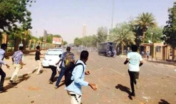 Students throw stones during a confrontation with the antiriot policemen in the University Street as they protest over government plan to transfer the premises of the University of Khartoum outside the capital, on Wednesday  April 13, 2016.