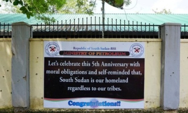 A sign celebrating five years of South Sudanese independence on a bullet-damaged wall opposite to the presidential palace in Juba on 15 July 2016 (AFP Photo)