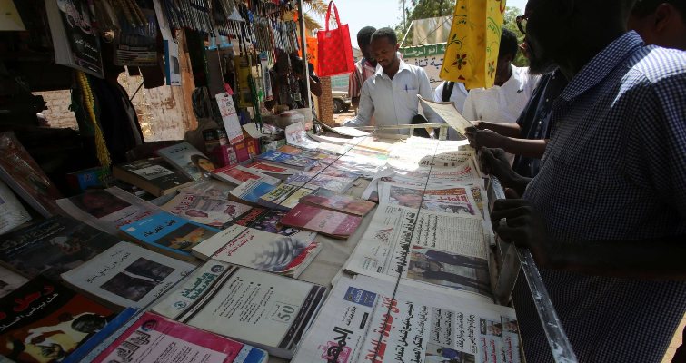 Sudanese men look at newspapers displayed at a kiosk in the capital Khartoum on February 16, 2015. (AFP Photo)