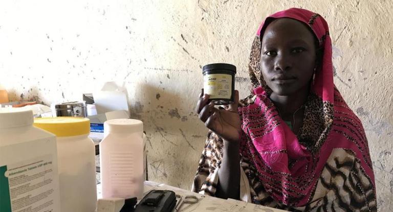 Mukuma Hamad, a volunteer health worker, holds a container of folic acid, the only assistance she can give pregnant women who visit the lone health clinic in Hadara village, in rebel-controlled Southern Kordofan (Skye Wheeler/ HRW Photo)