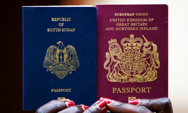 A woman poses for a photograph as she holds up two passports, one British and one South Sudanese, in Juba on July 6, 2012.  (Photo AFP/Giulio Petrocco)