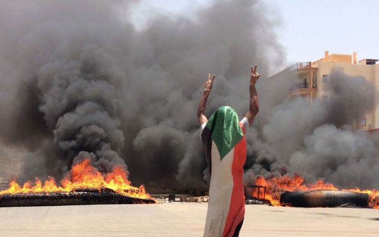 A protester flashes the victory sign in front of burning tires and debris on road 60, near Khartoum's army headquarters, in Khartoum, Sudan, Monday, June 3, 2019 (AP photo)