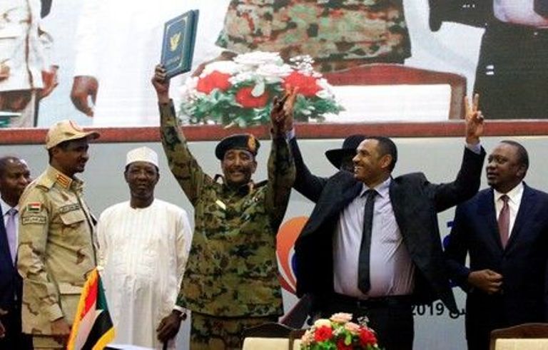 TMC head Abdel Fattah Al-Burhan and Ahmed Rabie of the FFC makes the V for victory at the signing ceremony of the agreement on the transitional authority on 17 August 2019 Reuters.jpg