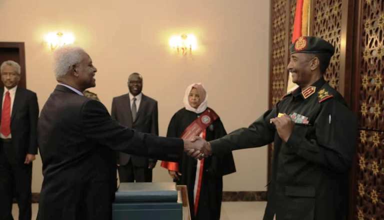 Attorney General Taj-Alsir al-Hebir (L) shakes hand with al-Burhan after taking oath of office on Sunday 13 Oct 2019 (Sovereign Council photo)