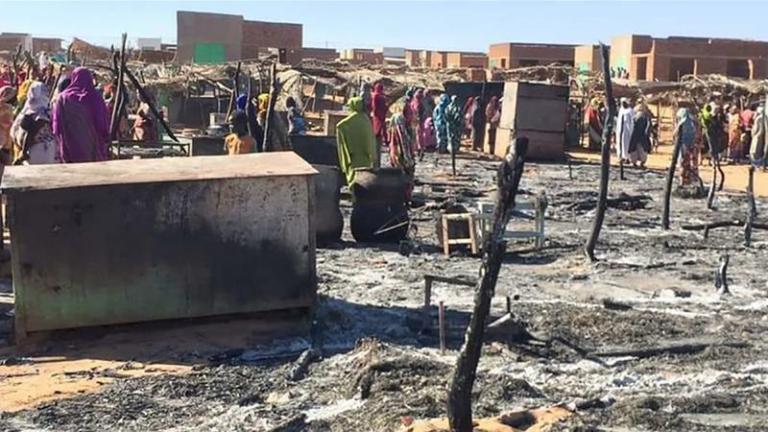 Residents of Krinding  IDP camp gather around the burned remains of makeshift structures in Geneina, Sudan (AP photo)