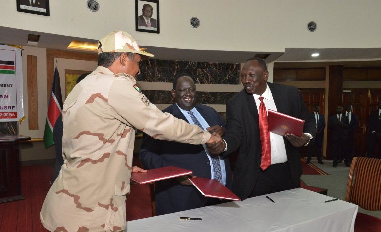 SPLM-N Al-Umda (R) shakes hands with Hemetti (L) after the signing of the peace framework agreement while Tut Gatluak (C) applauds on 24 January 2020 (SSPPU photo)