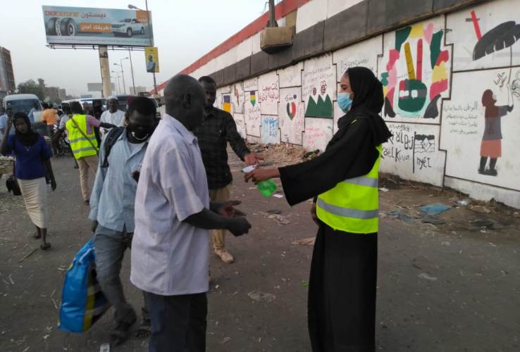 A volunteer disinfects passengers hands near a transport station in central Khartoum on Monday 16 March 2020 (ST photo)