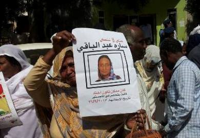 احدى قريبات الفقيدة سارة عبدالباقي ترفع صورتها امام المحكمة بعد تبرأة المتهم في 28 مايو 2014 (سودان تربيون)