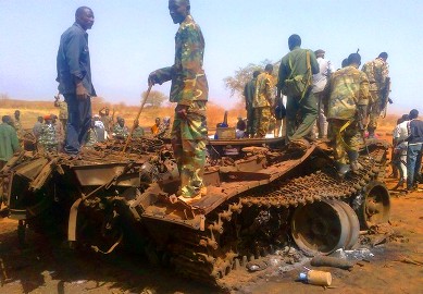 جنود سودانيون يقفون على متن دبابة مدمرة لجيش جنوب السودان بعد انسحابها من هجليج