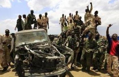 قوات من الجيش السوداني والدعم السريع حول عربة محطمة بعد سيطرتها على دلدكو في يوم 20 مايو 2014 (صورة رويترز محمد نورالدين)