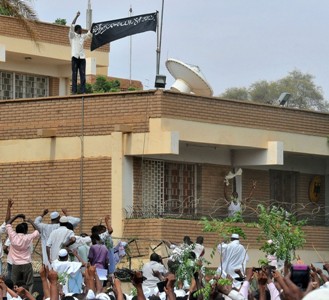 متظاهرون يرفعون علم اسم كتبت عليه عبارة لا الله الا الله في السفارة الالمانية في الخرطوم بعد اضرام النار في بعد من جوانبها واحتلالها
