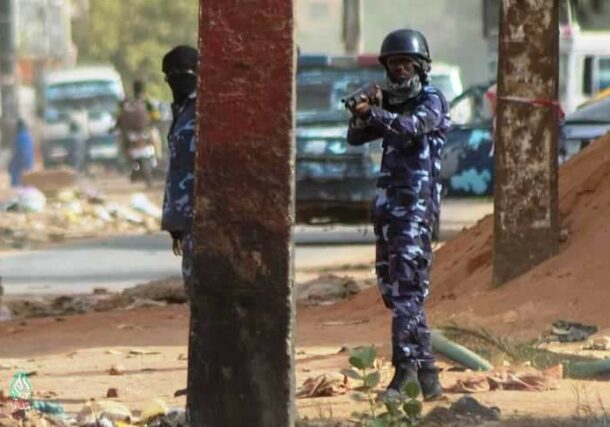 A policeman directs his gun to the proteters in Omdurman on May 21, 2022