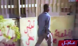 رجل يحمل مسدسا في يده اليمنى متجها صوب المتظاهؤين في شروني، الخرطوم، في 5 مايو 2022 (صورة من فيديو بثته قناة الحدث) 