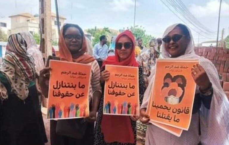 Sudanese women hold banners calling to abolish stoning sentence outside UNHCR in Khartoum on September 14, 2022