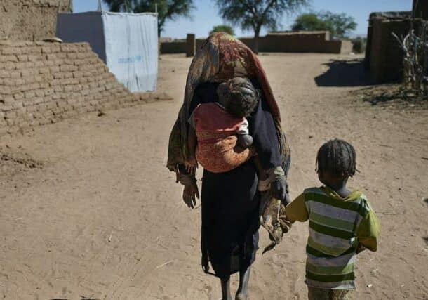A mother walks with her childern to a shelter at an IDP camp near El Fasher, the capital of North Darfur (UN file photo)