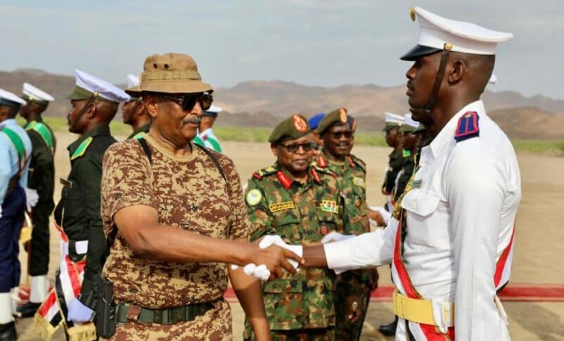 Al Burhan shakes hands with a graduated army officer in Gebit on July 31, 2024