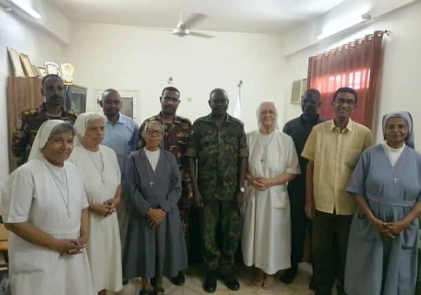 Five Italian nuns and a priest pose with the Sudanese army officer who supervised their evacuation from Al-Shajara suburb on August 6, 2024