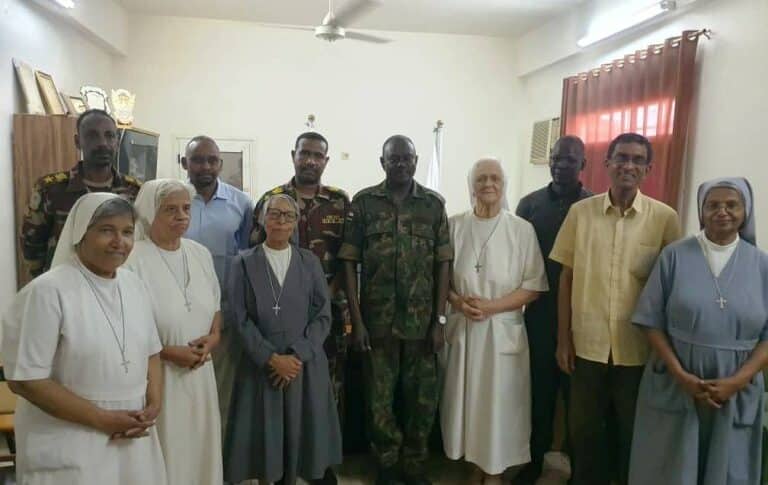 Five Italian nuns and a priest pose with the Sudanese army officer who supervised their evacuation from Al-Shajara suburb on August 6, 2024