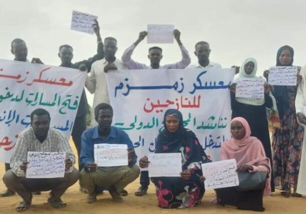 Zamazm residents hold banners calling to end the RSF siege on their camp on September 30, 2024
