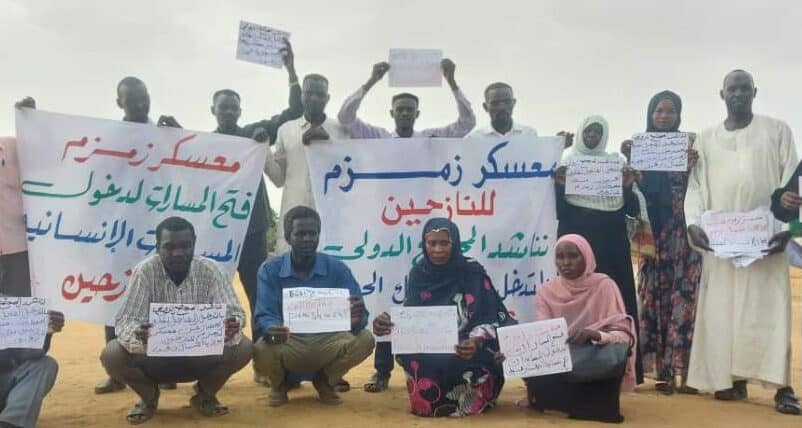 Zamazm residents hold banners calling to end the RSF siege on their camp on September 30, 2024