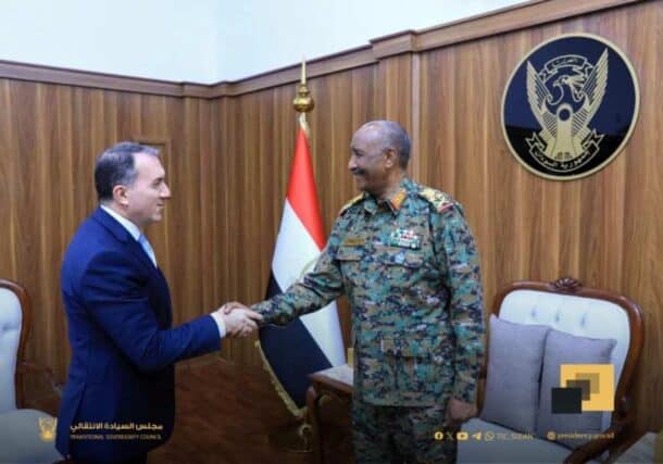 Sudan's leader Burhan shakes hands with the Turkish envoy while discussing projects, aid, and resuming flights.