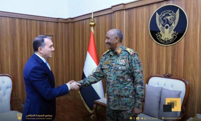 Sudan's leader Burhan shakes hands with the Turkish envoy while discussing projects, aid, and resuming flights.
