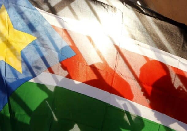 The silhouettes of South Sudanese people are seen through a South Sudanese flag as they line up to cast their votes in Juba, South Sudan, on Jan. 9, 2011. AP Photo