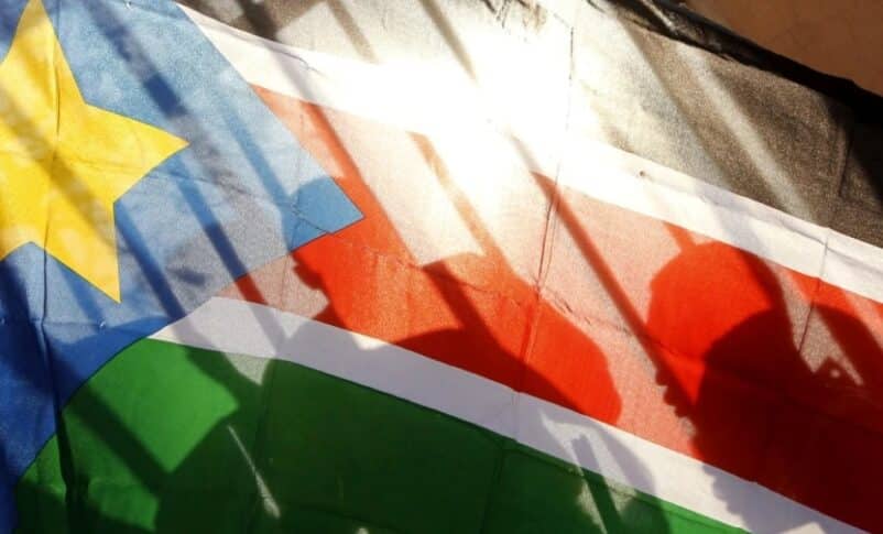 The silhouettes of South Sudanese people are seen through a South Sudanese flag as they line up to cast their votes in Juba, South Sudan, on Jan. 9, 2011. AP Photo