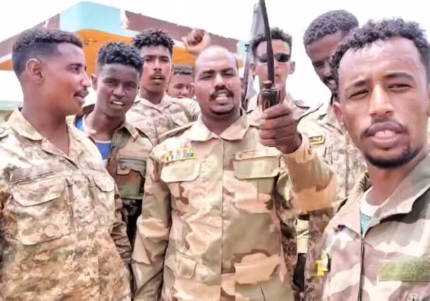 A commander of the Sudan Shield Forces gestures as he stands with his fighters near the site of a deadly drone attack in Tumbul, Sudan, August 13, 2025