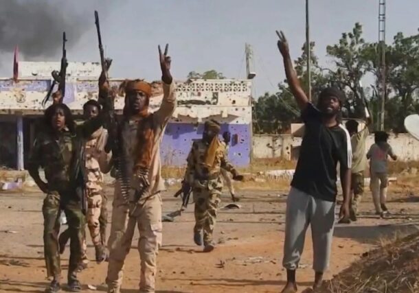 RSF fighters flash the victory sign outside the army headquarters in El Fasher on October 26, 2025.