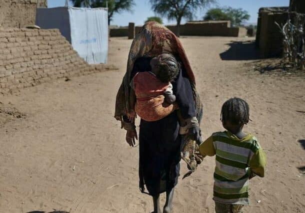 A mother walks with her children to their shelter at an IDP camp in North Darfur in March 2025, UNICEF photo