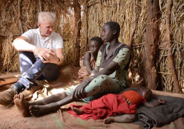 Secretary General of the Norwegian Refugee Council (NRC) Jan Egeland speaks to a displaced woman with her kids, NRC photo
