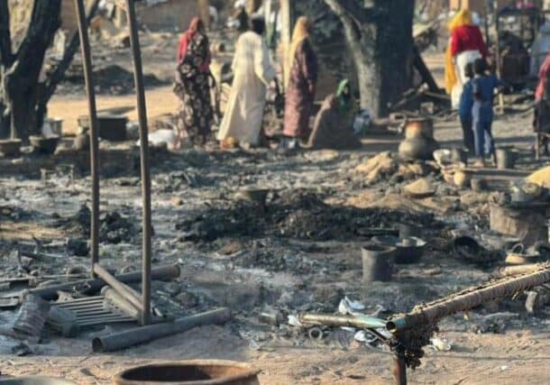 Displaced people inspect the charred remains of their belongings at Kalma camp in South Darfur on March 1, 2026, after a massive fire destroyed more than 1,000 makeshift shelters.