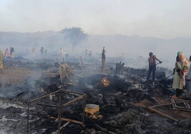 Residents stand among the charred remains of shelters and belongings following a fire at an IDP camp in Golo, Central Darfur, on April 27, 2026
