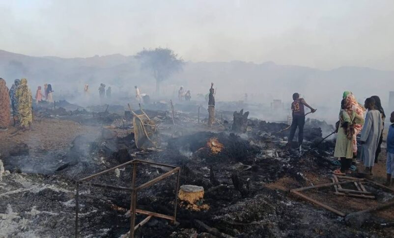 Residents stand among the charred remains of shelters and belongings following a fire at an IDP camp in Golo, Central Darfur, on April 27, 2026