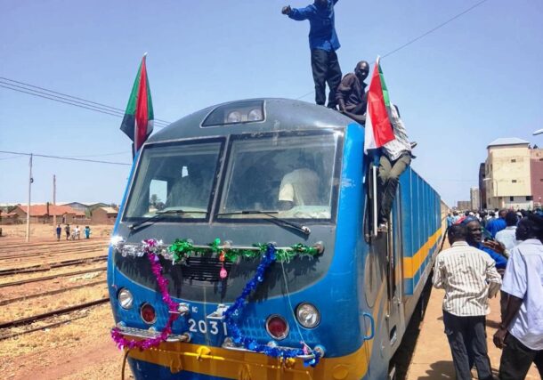 People celebrate on top of a decorated train as it arrives at the Wad Madani railway station on July 20, 2026, marking the first train service to reach the city since the outbreak of the conflict in April 2023.
