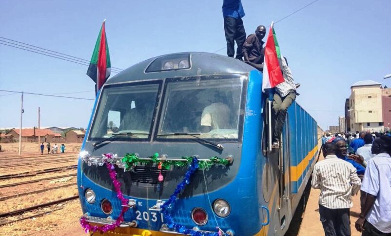 People celebrate on top of a decorated train as it arrives at the Wad Madani railway station on July 20, 2026, marking the first train service to reach the city since the outbreak of the conflict in April 2023.