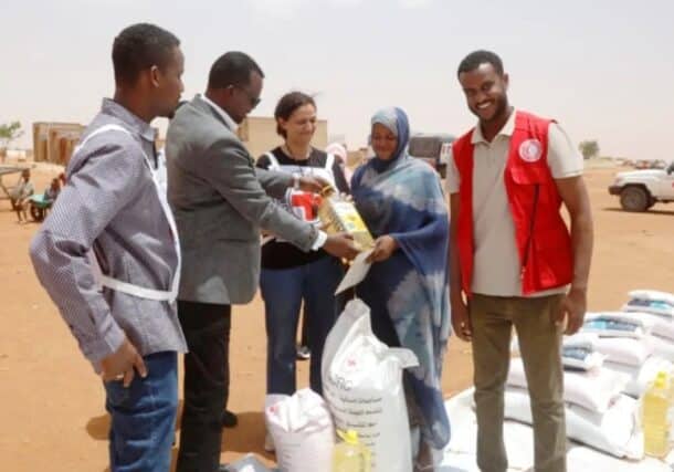 Red Cross workers deliver essential food items to a displaced woman in El Obeid