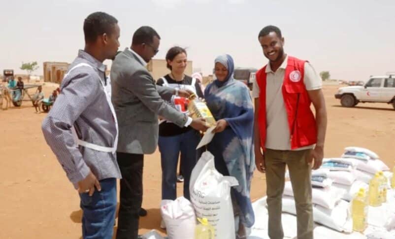 Red Cross workers deliver essential food items to a displaced woman in El Obeid