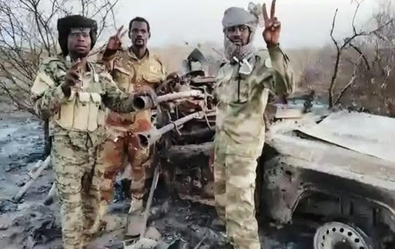 Joint Force members stand next to a destroyed RSF vehicle in Amburu, North Darfur, Aug. 13, 2026.