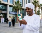 Sudanese expatriate in Saudi Arabia smiles while viewing a successful mobile banking transaction on his smartphone. (AI-generated image)