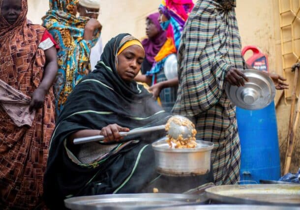 A Sudanese woman from a community kitchen distributes meals for people who are affected by conflict and extreme hunger, in Omdurman, Aug 22, 2024. Reuters