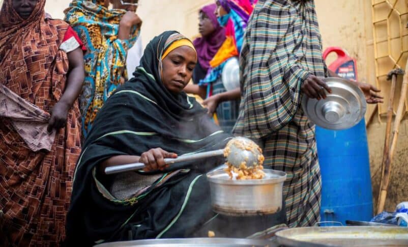 A Sudanese woman from a community kitchen distributes meals for people who are affected by conflict and extreme hunger, in Omdurman, Aug 22, 2024. Reuters